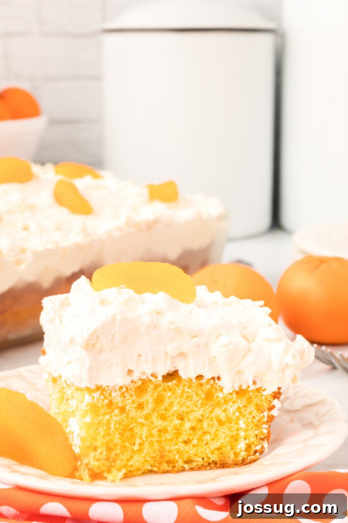 A vibrant slice of pineapple-orange cake on a plate, highlighting the fluffy topping and moist cake layers.