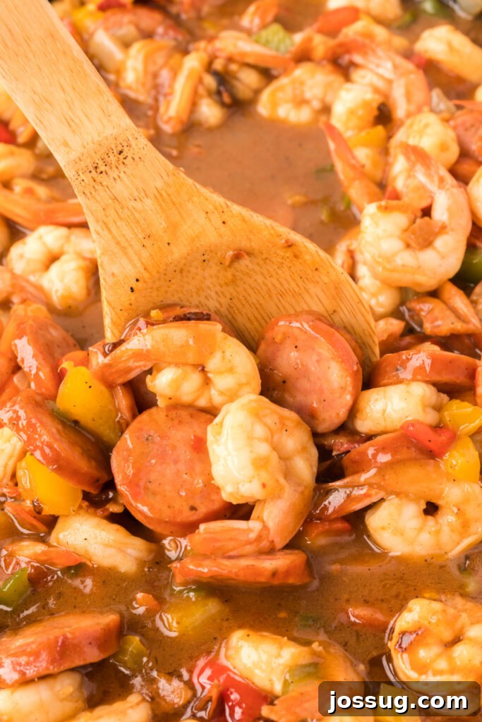 Carolina's Signature Shrimp and Grits 4 A close-up view of the rich and colorful shrimp, sausage, and vegetable mixture in a skillet, glistening with sauce.