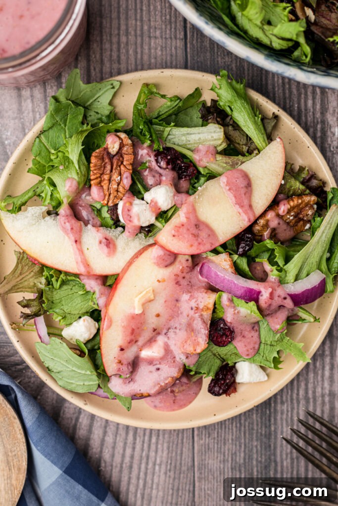Close-up of a vibrant Thanksgiving salad served on a plate, showcasing crisp apples, cranberries, feta, and bacon.