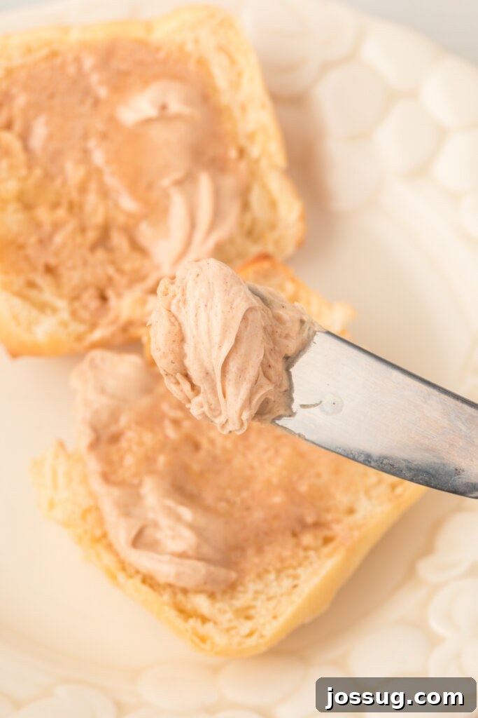 Close-up of creamy cinnamon butter being smoothly spread onto a dish with a knife, highlighting its luscious texture