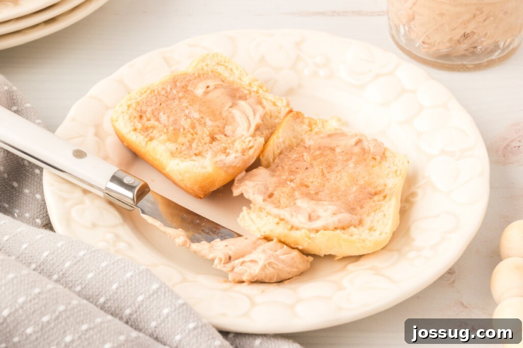 Golden-brown dinner roll generously spread with a thick layer of creamy cinnamon butter