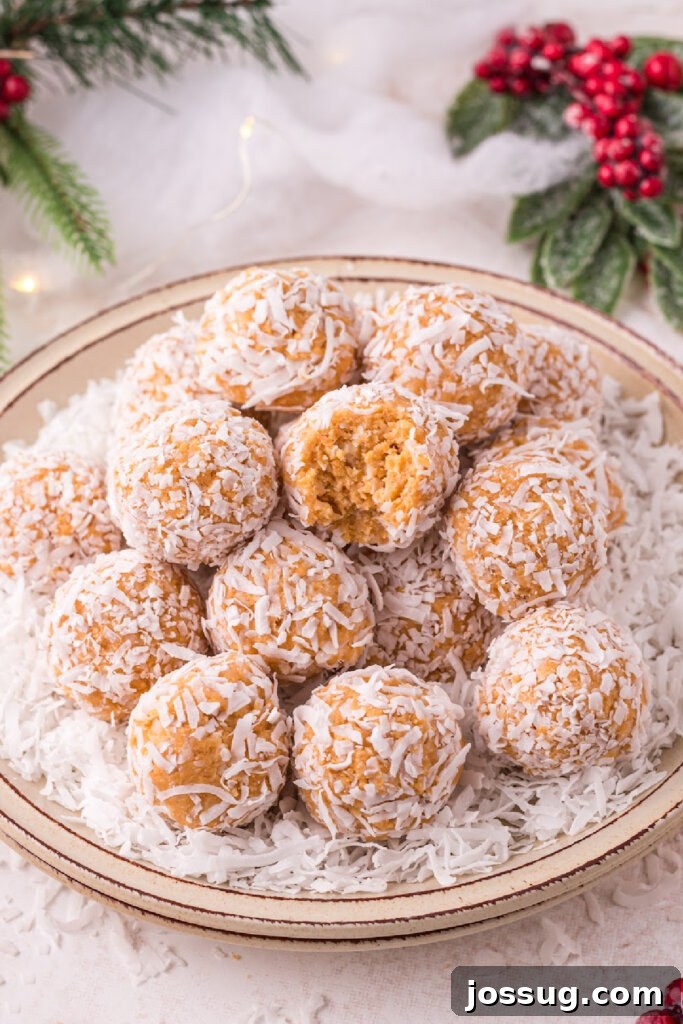 Coconut Bliss Bites 5 Stacked coconut snowballs on a plate, with one showing a bite mark, showcasing its soft interior