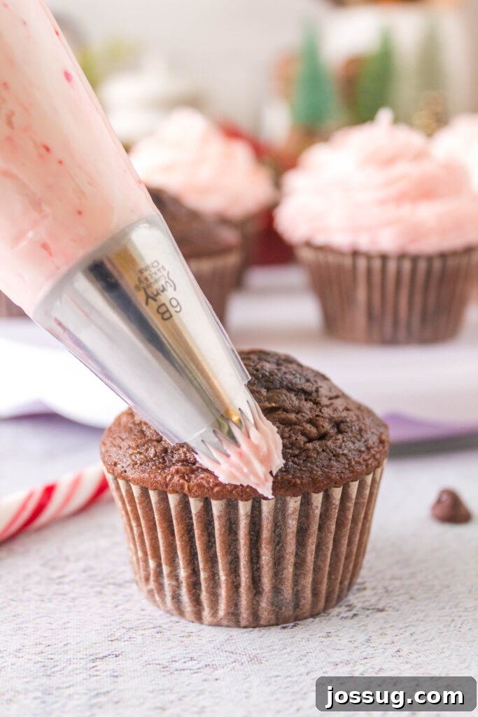 Peppermint Swirl Chocolate Cupcakes 4 Adding peppermint candy cane frosting onto a freshly baked chocolate cupcake