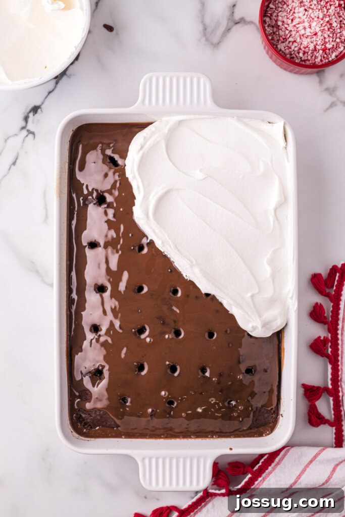 Peppermint Dream Poke Cake 4 spreading the topping over the chocolate layer