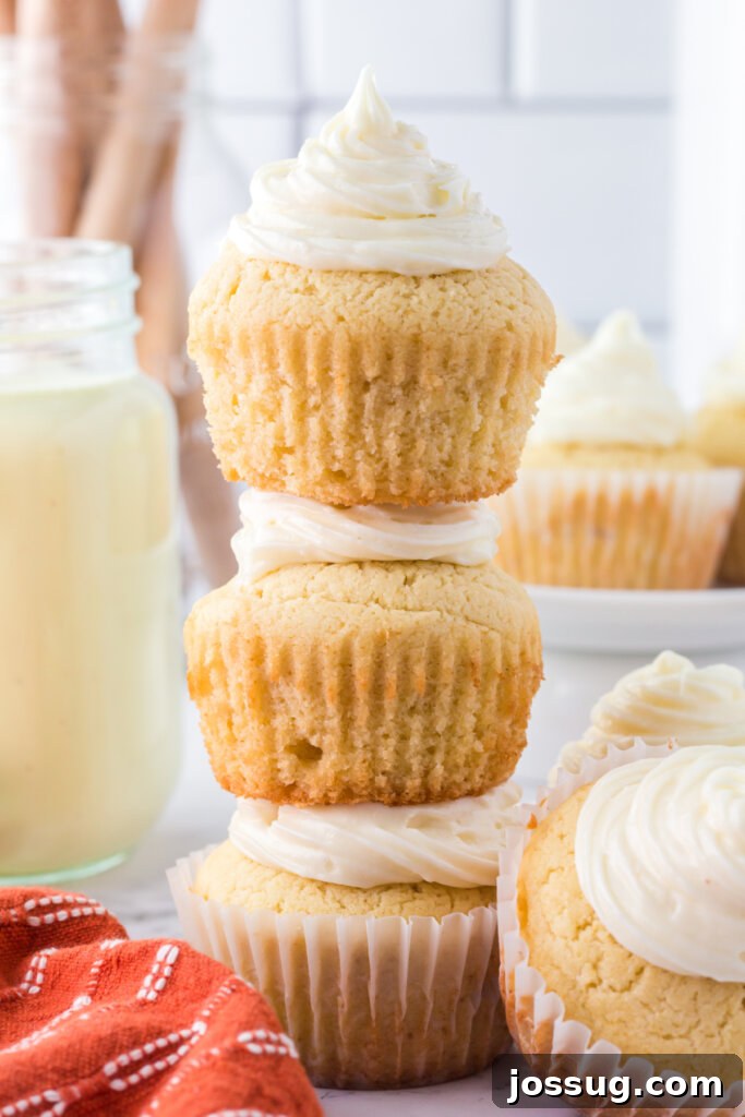 Festive Eggnog Cupcakes 4 A stack of three beautifully frosted eggnog cupcakes, garnished with a sprinkle of nutmeg, creating an inviting holiday display.