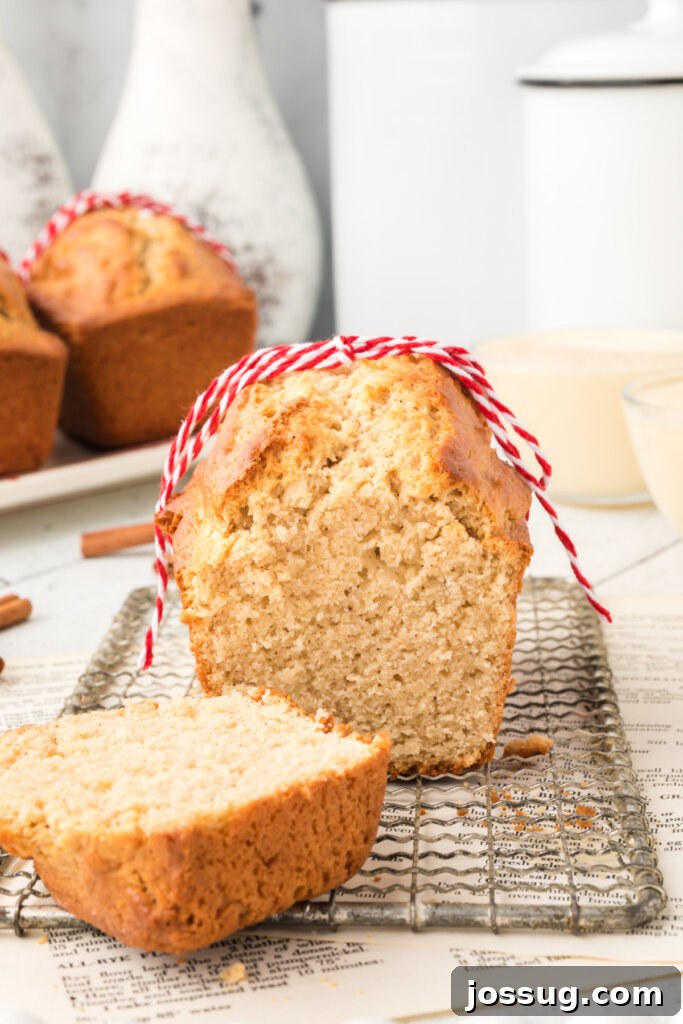A freshly baked loaf of Holiday Eggnog Bread with a slice removed, revealing its moist, golden interior and inviting texture.