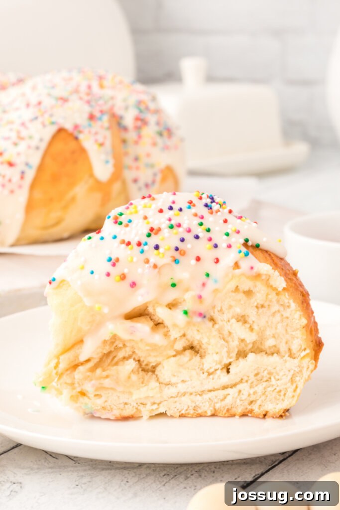 A perfectly baked, frosted Italian anise bread slice on a pristine white plate, showcasing its fluffy texture and inviting glaze.