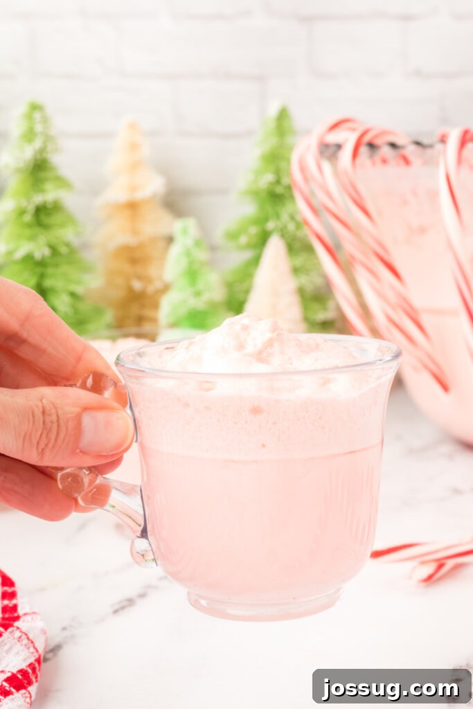 hand holding a glass full of festive peppermint eggnog punch