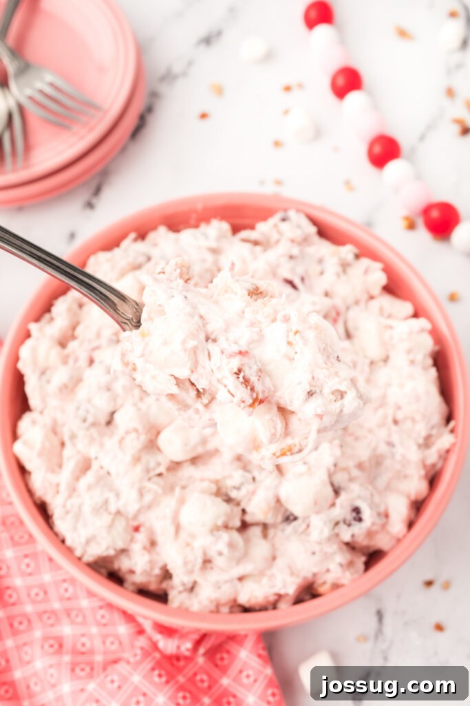 cranberry fluff salad in pink bowl with a spoon