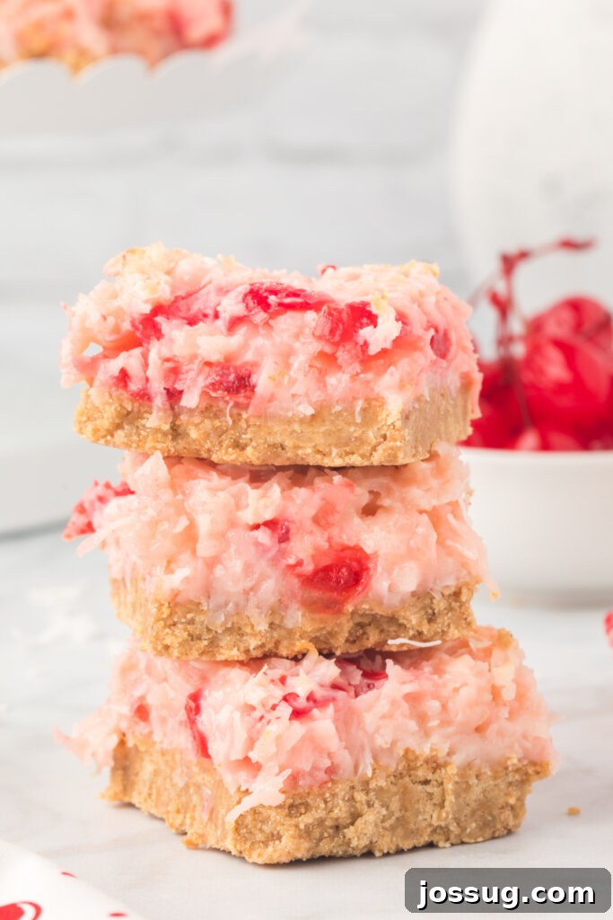 Three decadent Cherry Coconut Magic Bars stacked, showcasing their layers and vibrant cherry specks.