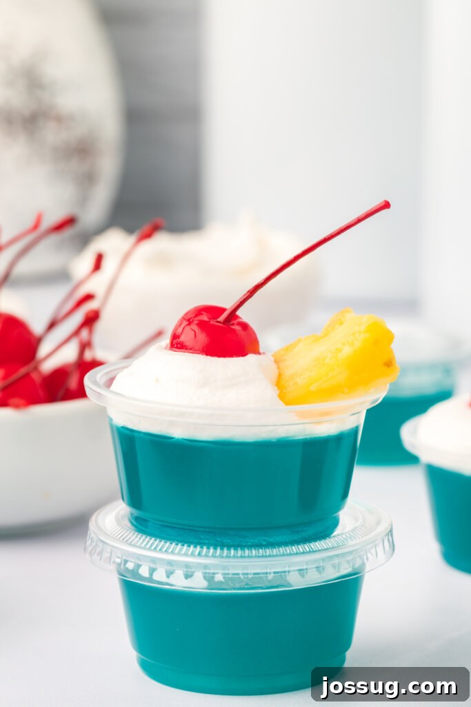 Aloha Glow Gels 2 Two vibrant blue Hawaiian jello shots, stacked for a playful presentation, garnished with tiny umbrellas.