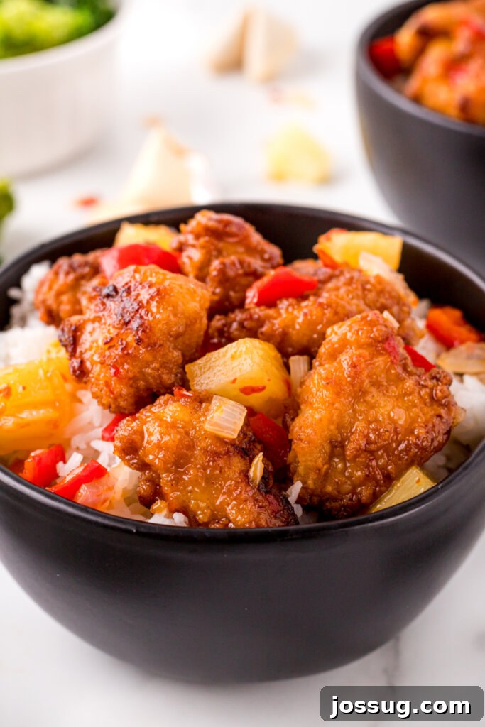 Copycat Sweet Fire Chicken - Aromatic and Flavorful Close-up of vibrant Copycat Panda Express Sweet Fire Chicken in a black serving bowl, garnished with sesame seeds and fresh cilantro.