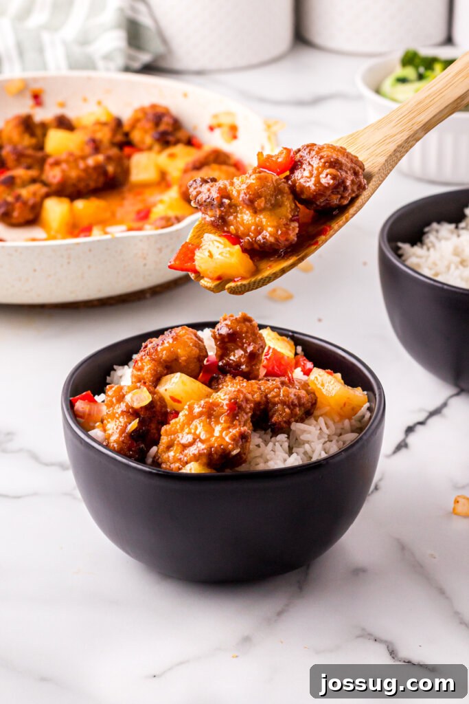 Homemade Sweet Fire Chicken – Quick and Easy Meal Prep A dish of freshly cooked sweet fire chicken being transferred into an elegant black bowl, highlighting the colorful ingredients.