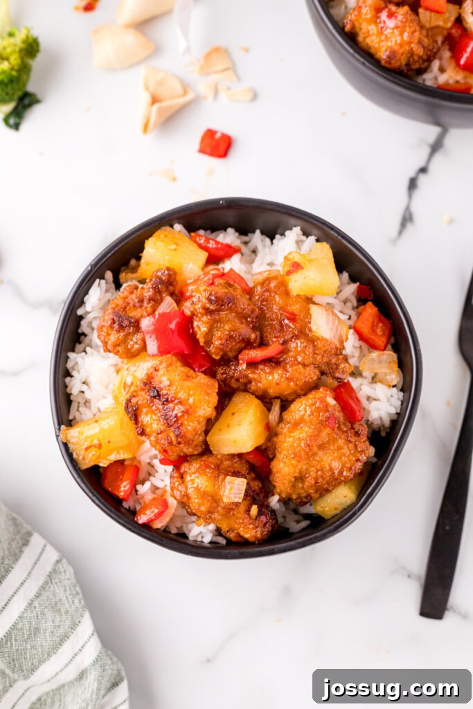 Delicious Sweet Fire Chicken - Ready to Serve Overhead shot of a black bowl filled with Copycat Sweet Fire Chicken, showcasing the glistening sauce and perfectly cooked chicken and vegetables.