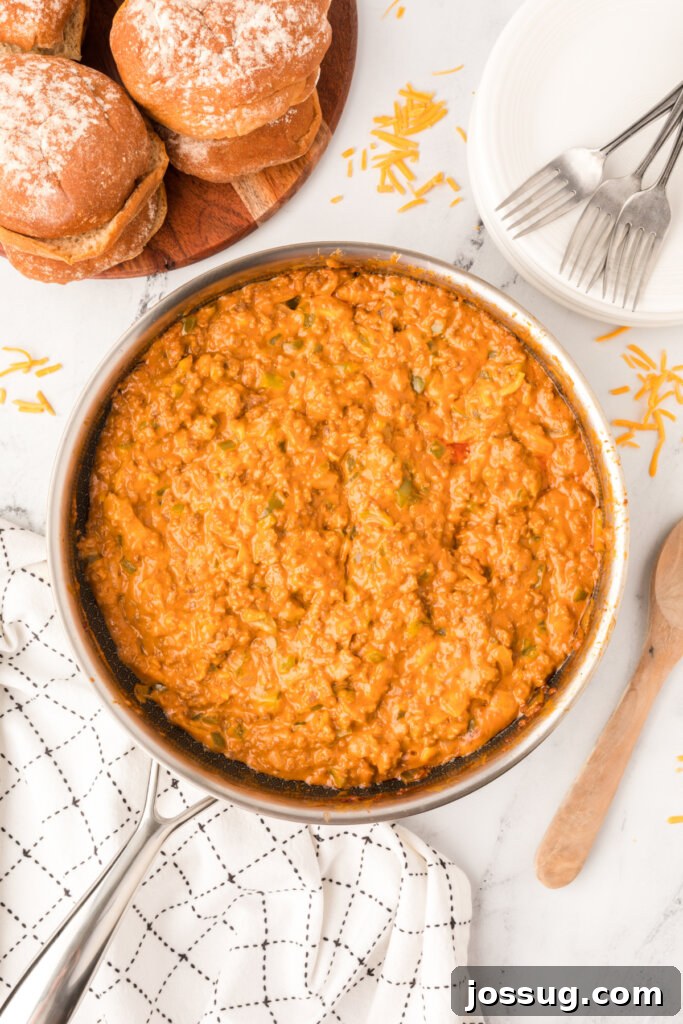 Golden Cheesy Sloppy Joes 3 A cast-iron skillet filled with a bubbling, rich cheesy sloppy joe meat filling, ready to be served on toasted buns.