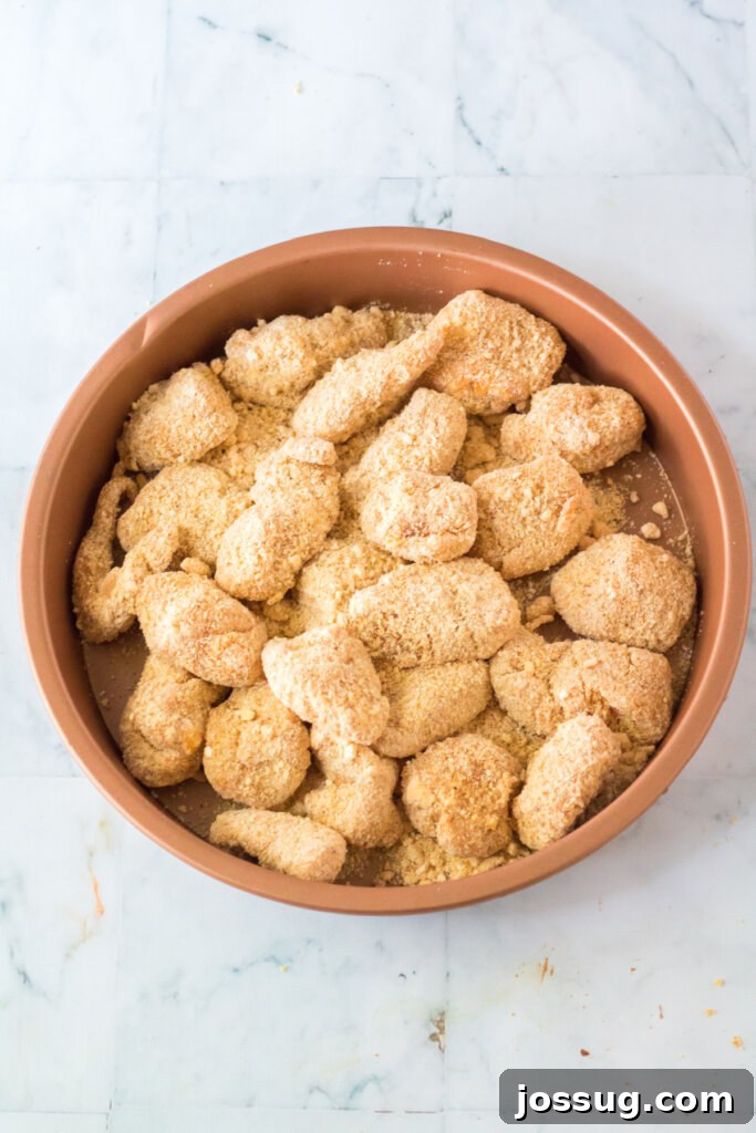 Chicken pieces, fully breaded and ready to be fried, arranged neatly in a bowl.