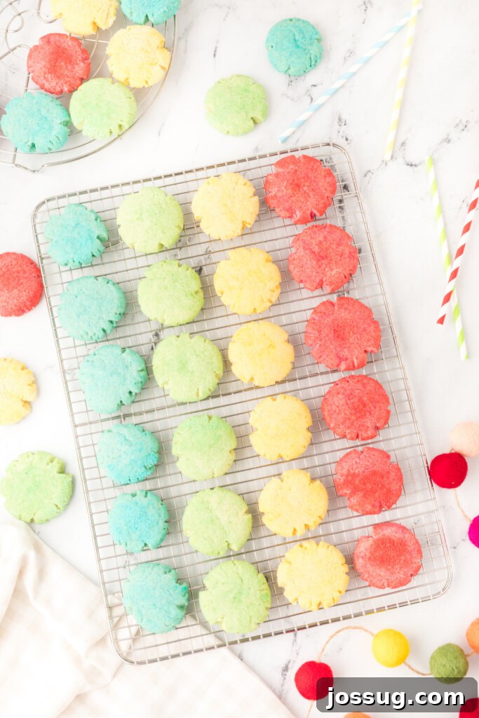 Four different colors of freshly baked Jello cookies cooling on a wire rack