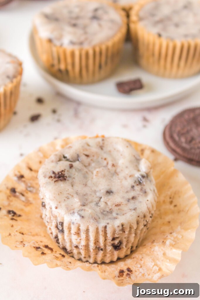 A single Oreo Cheesecake Cupcake, carefully unwrapped and ready to be enjoyed, showcasing its perfectly set and creamy cheesecake filling atop a dark Oreo crust.
