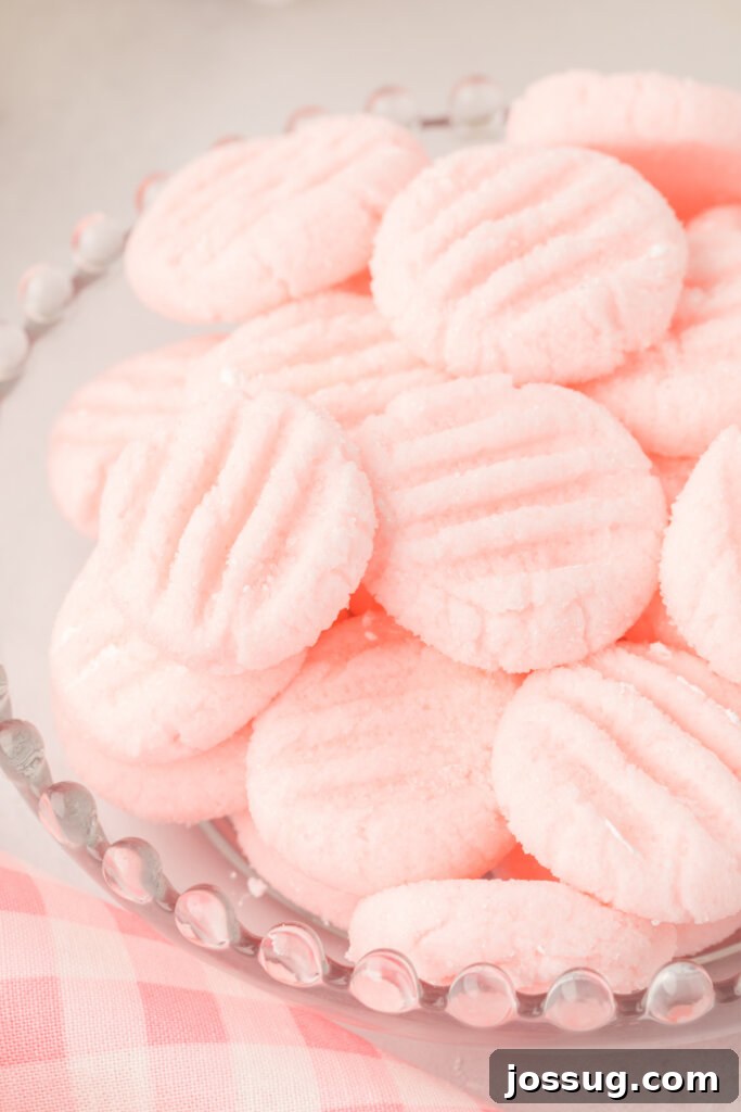 Velvet Mint Bites 2 Vibrant pink cream cheese mints elegantly arranged in a clear glass bowl, showcasing their soft, inviting texture.
