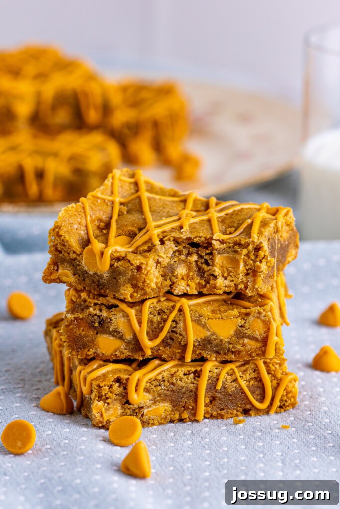 three butterscotch blondies stacked on top of each other, showcasing their moist texture and golden hue