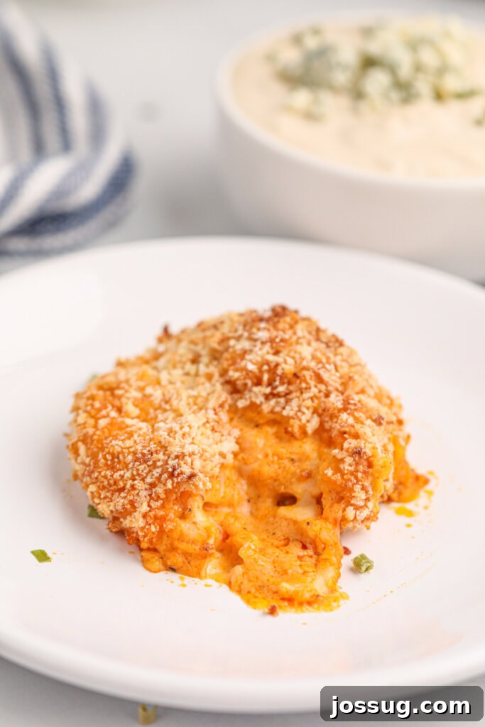 A close-up of a bitten buffalo chicken popper, revealing the creamy, cheesy, and spicy chicken filling inside.