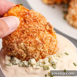 A buffalo chicken popper being dipped into creamy blue cheese sauce, highlighting the delicious pairing.
