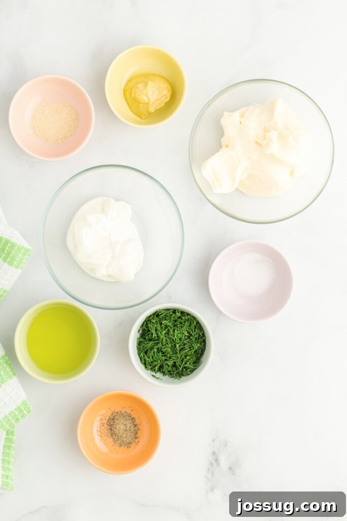 Fresh ingredients for dill pickle salad dressing laid out, including mayonnaise, sour cream, and dill