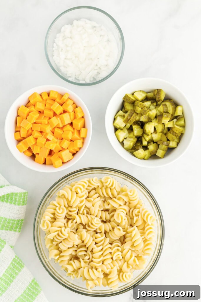 Assortment of fresh ingredients for dill pickle pasta salad on a wooden board