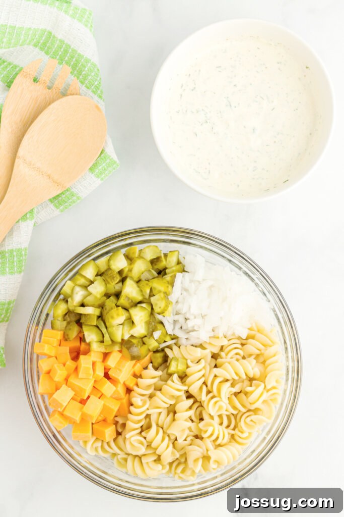 Dill pickle pasta salad and dressing in separate bowls, ready to be mixed