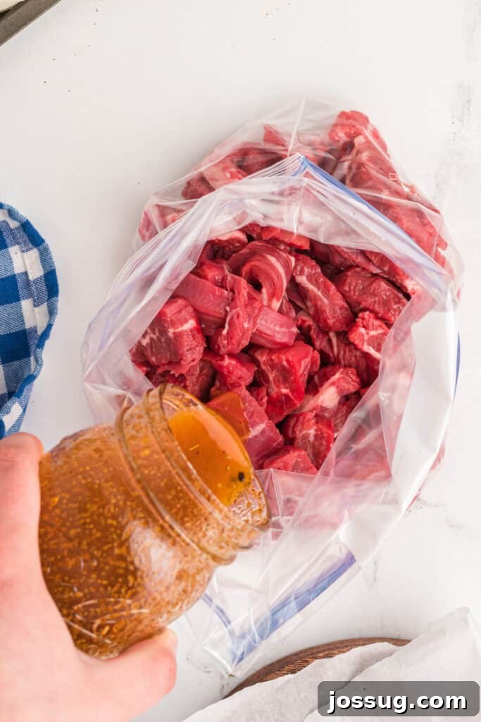 Marinated steak being poured into a plastic bag filled with sliced flank steak for fajitas