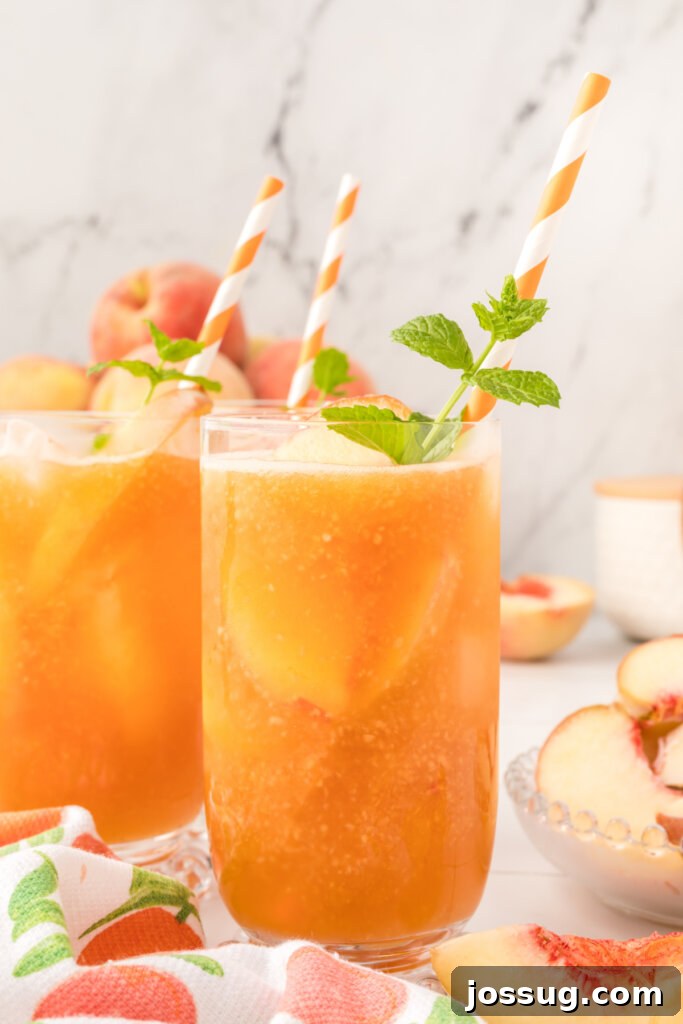 A glistening glass of iced Southern Peach Tea, garnished with fresh peach slices and mint, invitingly cool for summer.
