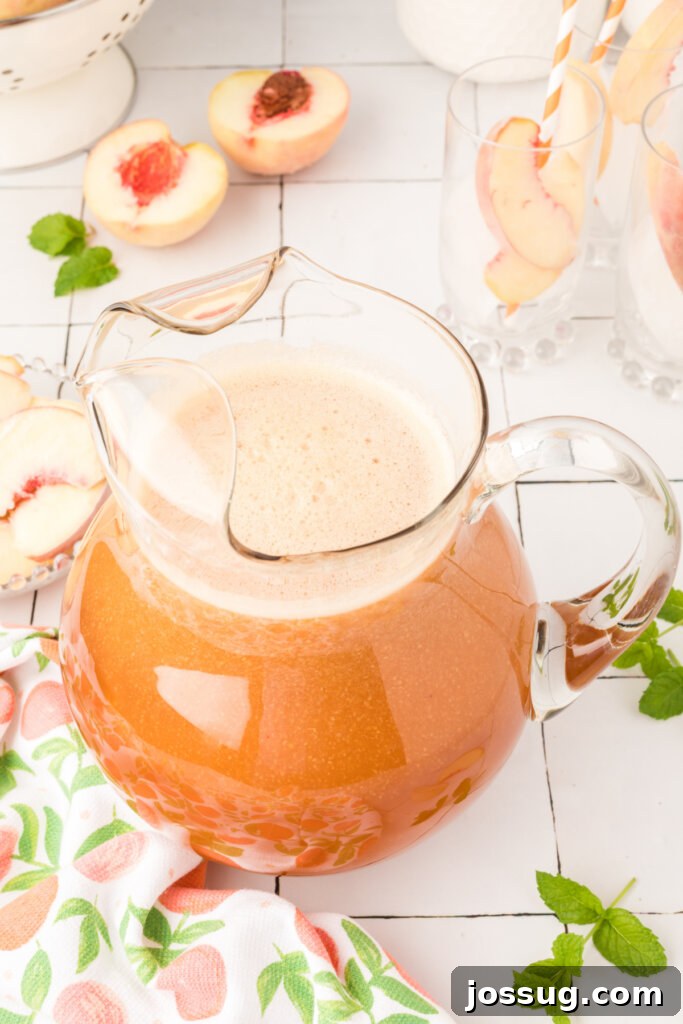 An overhead view of a large glass pitcher filled with golden Southern Peach Tea, ready to be poured and enjoyed.