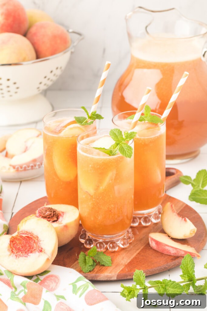 Four glasses of Southern iced peach tea, adorned with peach slices and mint, arranged on a wooden serving tray, promising a delicious refreshment.