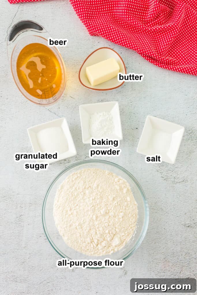 No-Knead Beer Bread 3 Ingredients laid out on a countertop, including flour, sugar, baking powder, salt, a stick of butter, and a bottle of beer, ready to make Beer Quick Bread.