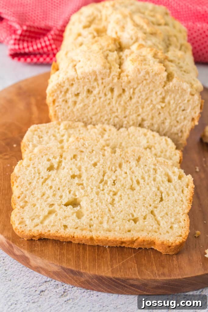 No-Knead Beer Bread 5 A close-up shot of a single slice of Beer Quick Bread, showing its fluffy texture and golden crust, next to a full loaf.