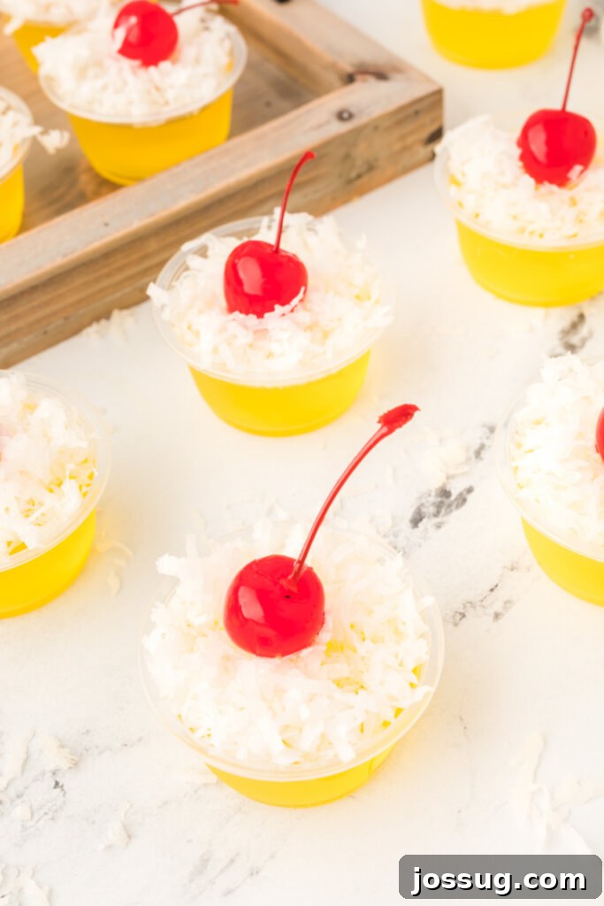Paradise Piña Jiggle Shots 4 looking down onto a pina colada jello stot topped with shredded coconut and a maraschino cherry