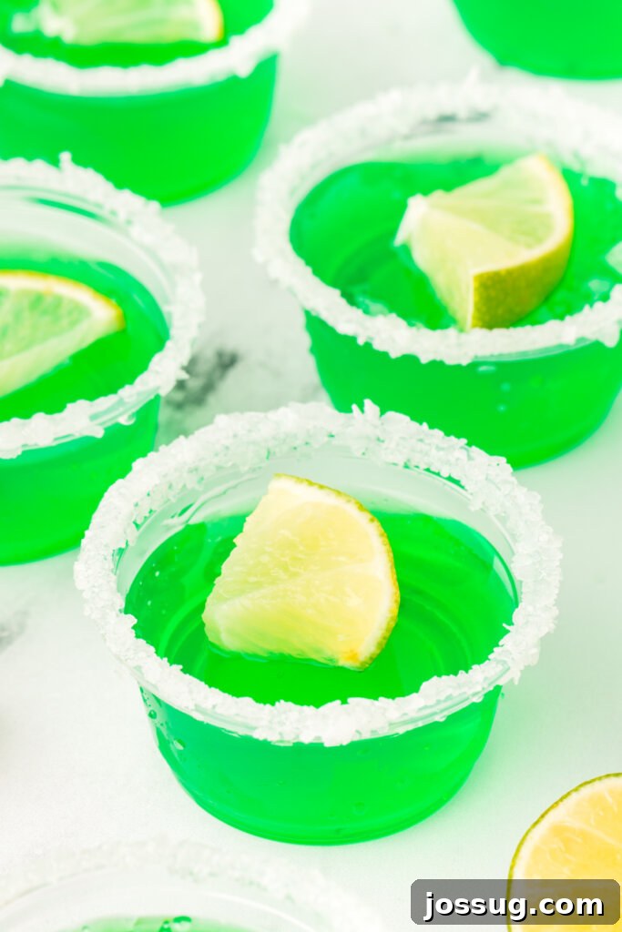 Several vibrant green lime margarita jello shots arranged neatly on a table, ready to be served at a party.