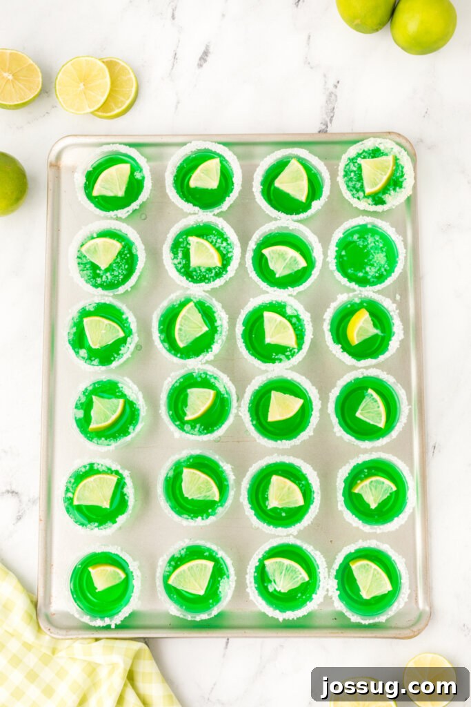 A tray filled with multiple green lime margarita jello shots, perfectly set and ready for guests to enjoy.