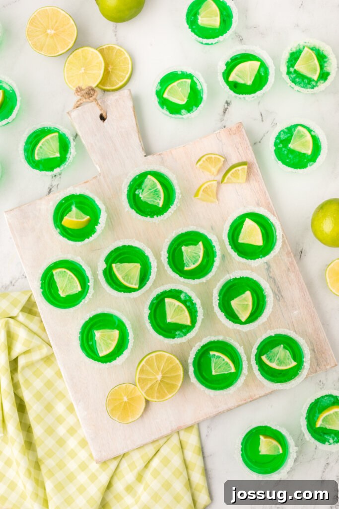An overhead view of a table adorned with numerous green lime margarita jello shots, artfully arranged for a vibrant party spread.