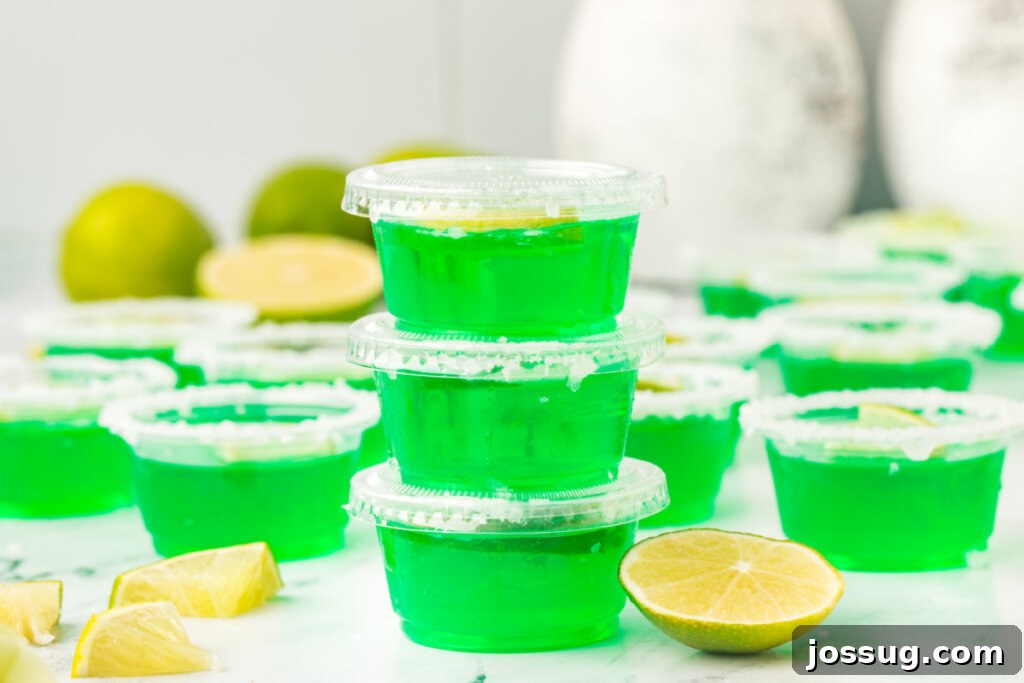 A trio of lime margarita jello shots, meticulously stacked, showcasing their inviting green hue and festive garnishes.
