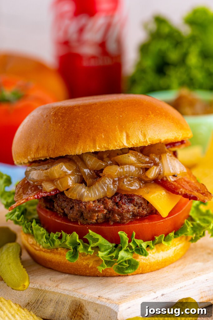 Coke-Glazed Onion Bacon Cheeseburgers 2 Closeup of a succulent bacon cheeseburger with a generous topping of glossy Coca-Cola onions, ready to be enjoyed.