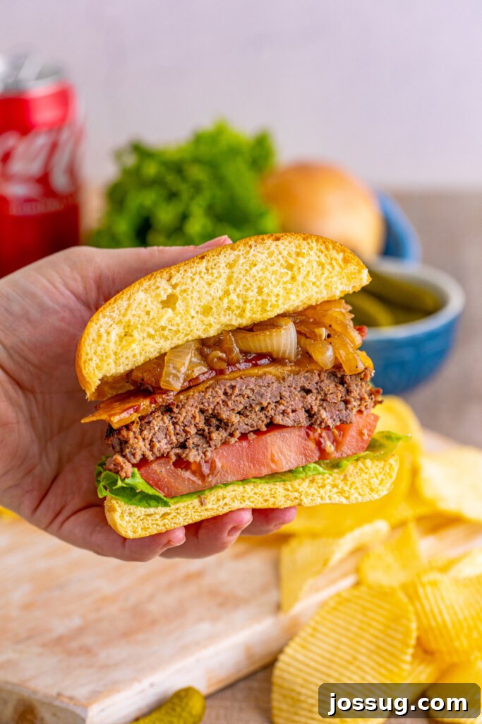 Coke-Glazed Onion Bacon Cheeseburgers 5 A close-up shot of a halved bacon cheeseburger with Coca-Cola onions, revealing the delicious layers inside.