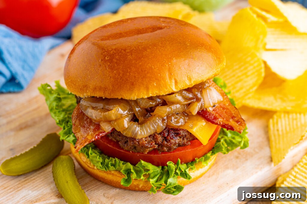 Coke-Glazed Onion Bacon Cheeseburgers 6 A delicious bacon cheeseburger served on a wooden cutting board with a side of crispy potato chips.