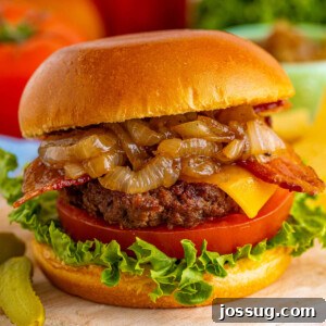 Closeup of an assembled bacon cheeseburger with caramelized onions, showcasing its delicious layers