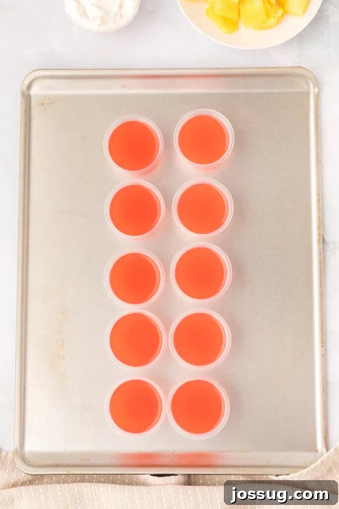 Caribbean Rum Jelly Shooters 4 Several vibrant rum punch jello shots arranged neatly on a baking sheet, ready for chilling.
