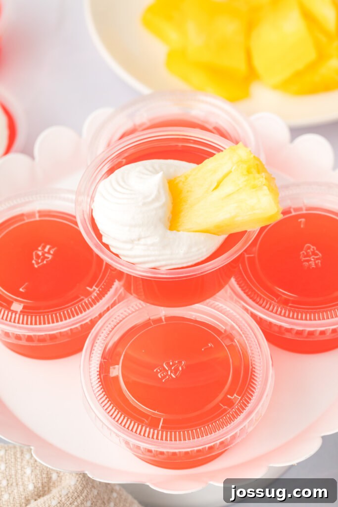 Caribbean Rum Jelly Shooters 5 A top-down view of beautifully garnished rum punch jello shots, complete with whipped cream and pineapple, ready for serving.