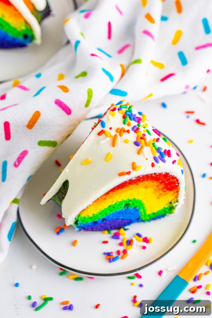 A close-up shot of a sliced Rainbow Bundt Cake, highlighting the perfect separation of colors.