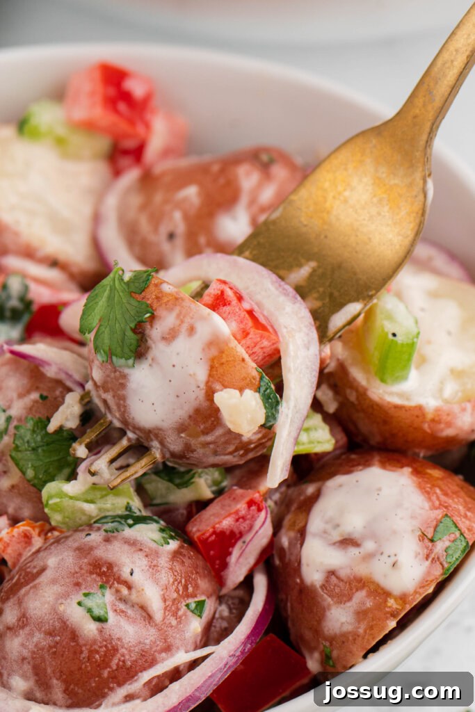 Fork picking up a spoonful of creamy Red Potato Salad with chunks of red potato