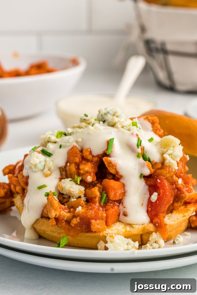 An open Buffalo Chicken Sloppy Joe, showcasing the rich filling, blue cheese crumbles, and ranch dressing.