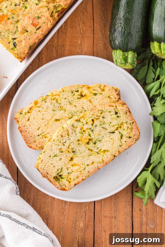 Savory Zucchini Cheese Loaf 4 Several slices of cheesy zucchini bread arranged on a white plate, revealing the melted cheese and flecks of green zucchini.